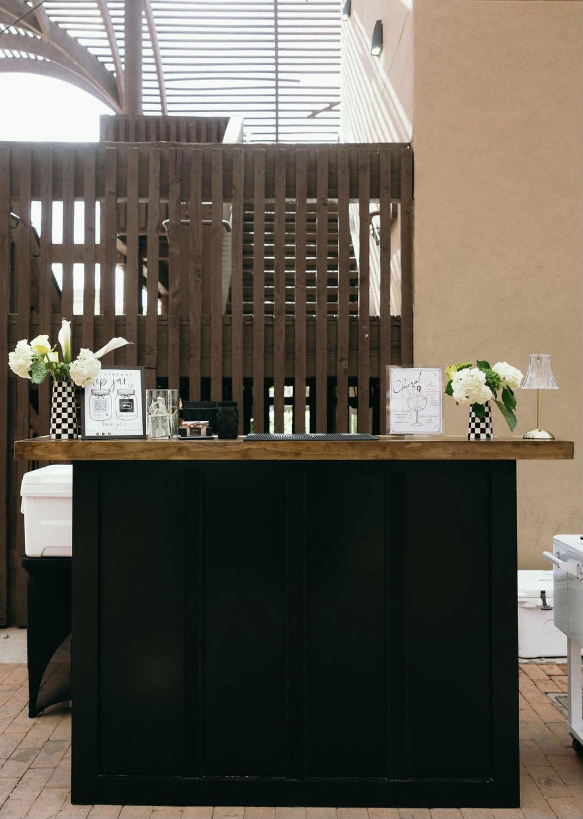 Black Sunset Sips mobile bar with a wood countertop at an event venue