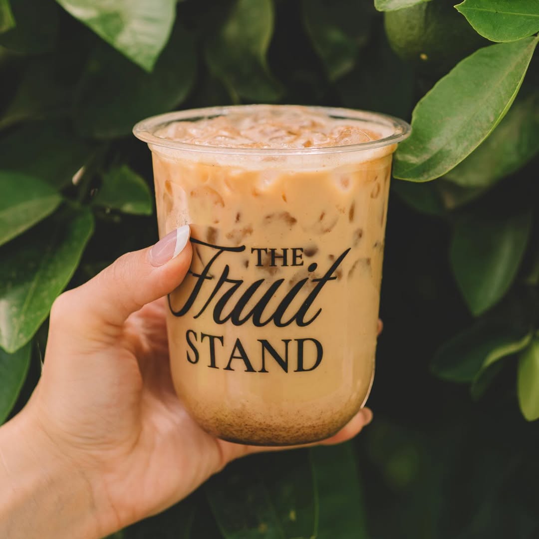 Iced latte from The Fruit Stand held in front of greenery