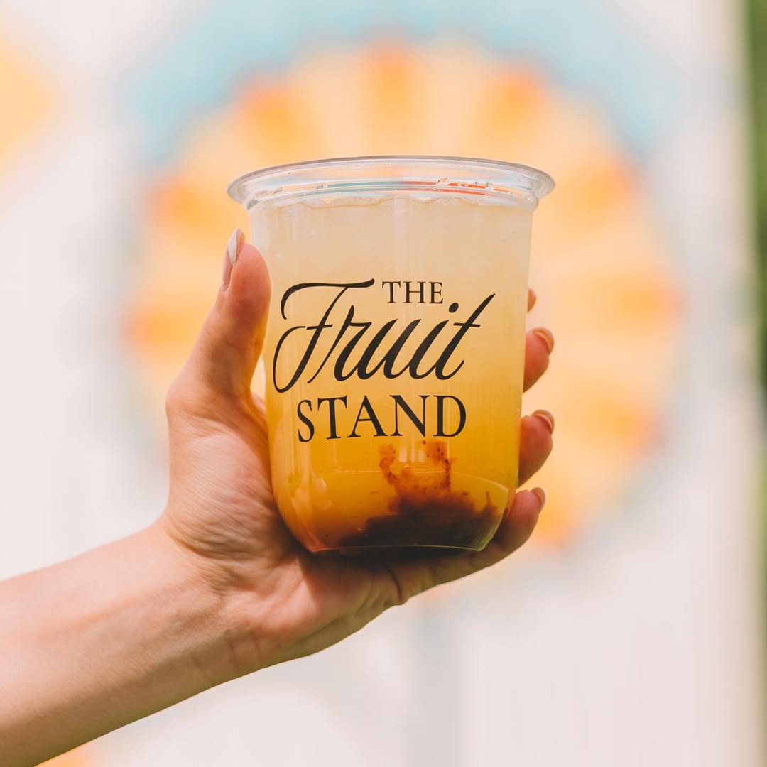 Fruit Stand drink cup held in front of a fruit display